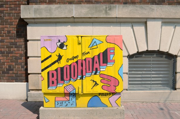 painted bell box near east entrance to Dufferin station, Greetings from Bloordale, yellow background with pink and blue images on it 