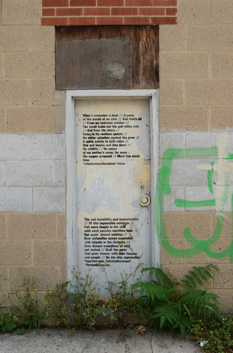 a white door on a concrete block wall in an alley with poetry written on it 