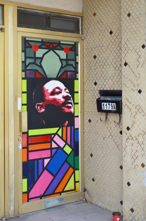 door alcove with small beige tiles, a black mailbox with number 11 on it, and an image of Martin Luther King and stained glass patterns on the door 