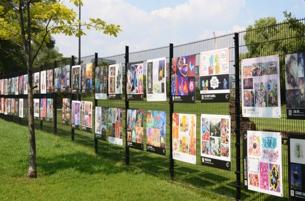a section of fence around Fort York with artwork on it, exhibit of OCADU gradex for graduating illustration students