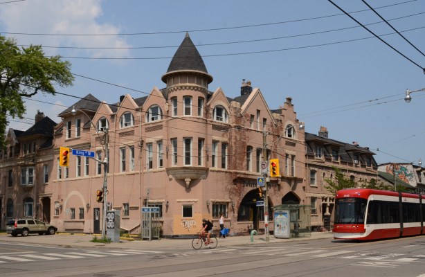 pinkish Palace Arms Hotel boarding house at King and Bathurst, with new TTC streetcar beside it
