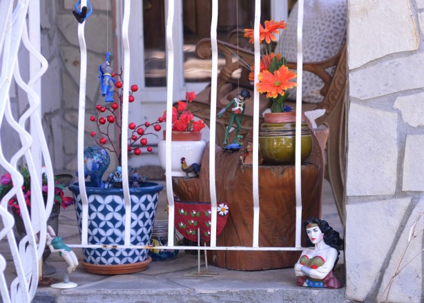 toy characters decorating a porch, upper body of wonder woman with her arms crossed in front of her, also pots of plants