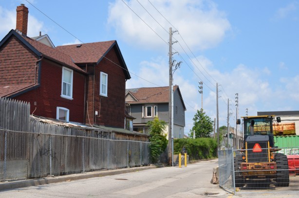 red house and a grey house on dead end street behind chainlink fence