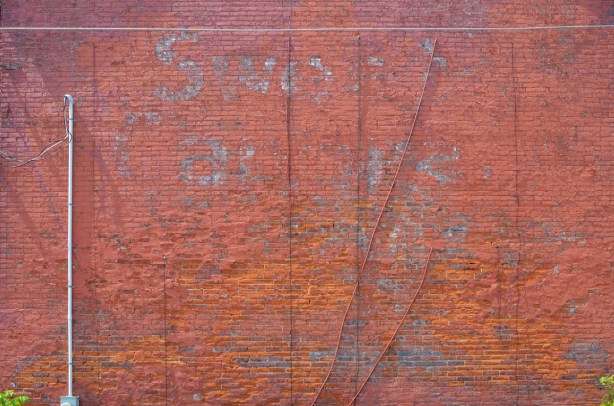 red brick wall with ghose sign for sweet caporals
