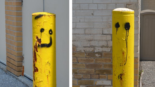 two yellow half posts in a parking lot, one with happy face and one with crying eyes 