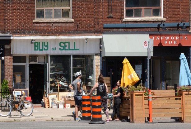 people on sidewalk talking, in front of Buy and Sell junk store