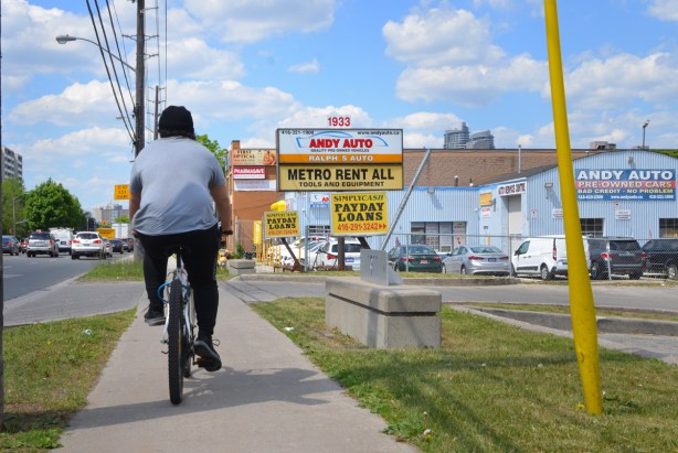 a man rides his bike on the sidewalk on Kennedy Road with back to camera