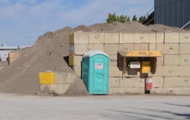 port a pottie by a wall holding back a pile of sand