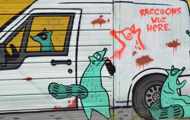 part of a mural by Emily May Rose of green raccoons vandalizing a van with spray paint and graffiti