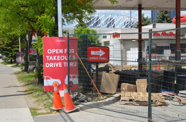 construction fence around a Tim Hortons and Petro Canada station, sign says open for takeout and drive thru