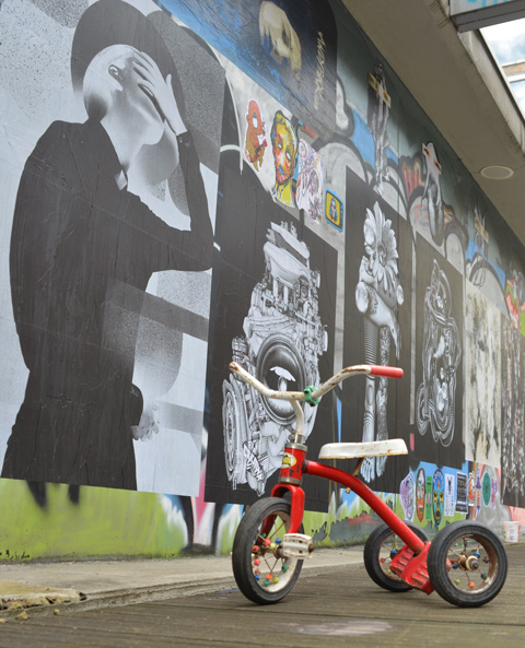 red trike in front paste platz, wheatpaste papers on a wall