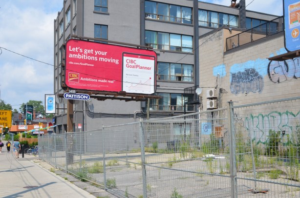 billboard in vacant lot with chainlink fence around it 
