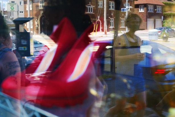 reflection in window of man walking past, red high heel shoes in the window 