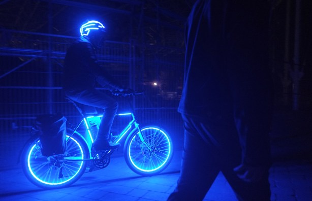 a man riding a bike at night with blue LED lights all over it. his helmet has lights too