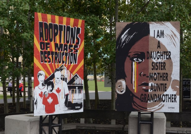 2 posters, adoption of mass destruction, and I am a mother sister auntie grandmother, protest signs on indigenous rights and past Canadian history of abuses