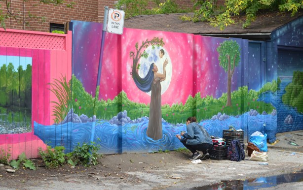 laneway mural by Scarbrite Collective and Memengwaa Originals, a mother lifts her baby up backlit by full moon on a pink sky