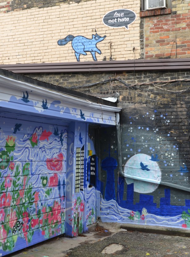 murals in a lane in Riverside near Queen and Broadview, Toronto. raccoon on upper story approaching a window, night scene on lower floor with bird silhoutted by full moon
