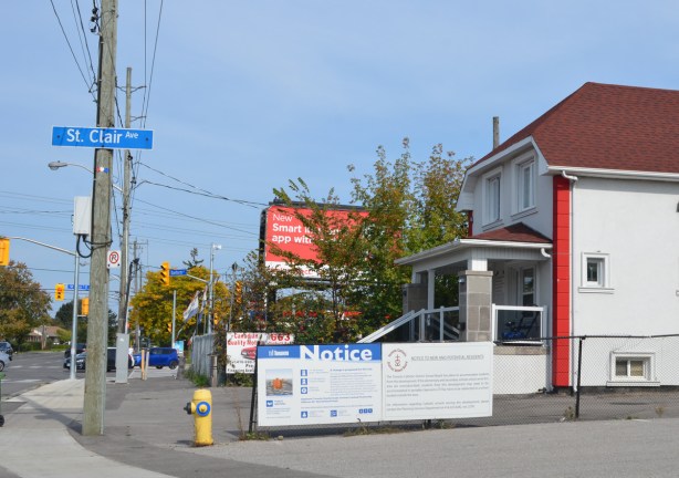 white house, now a commecrial business on St. Clair Ave with a blue and white development notice in front