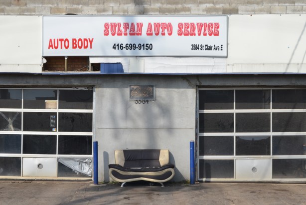 old car seat sitting outside of Sultan Auto Service, closed garage doors