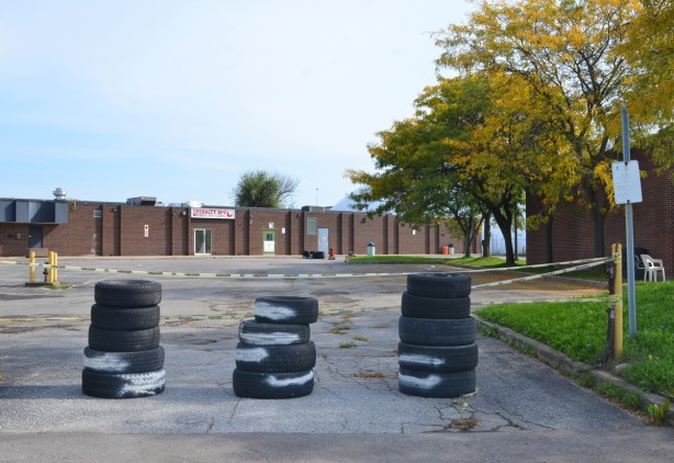 three piles of old tires blocking the driveway entrance to a light industrial site