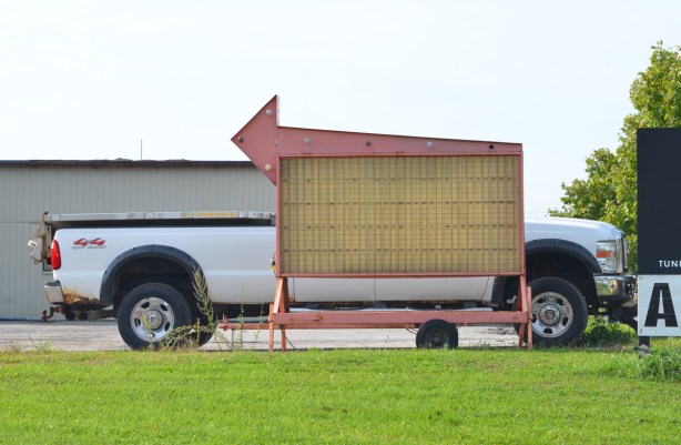 a white pick up truck parked behind a black sign with an arrow pointing left
