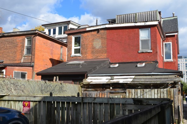 backs of upper levels of red brick houses, seen from an alley behind