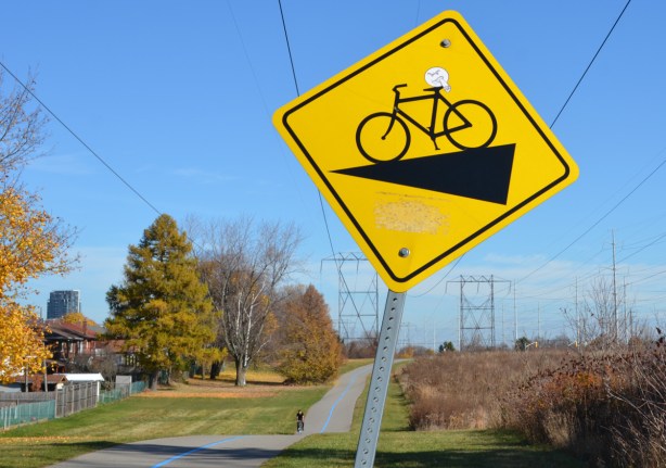yellow sign warning cyclists that there is downhill section ahead