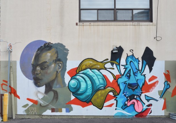 street art painting of a woman's profile by luvs beside a 