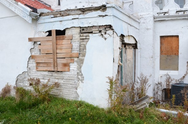 boarded up window and door on old white abandoned house