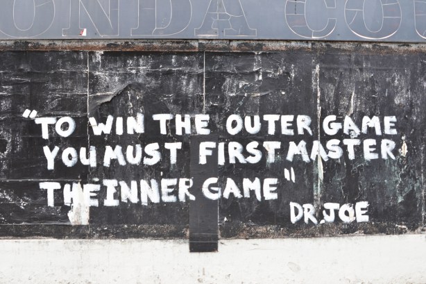 exterior wall of empty honda dealership, word graffiti that says to win the outergame you must first master the inner game, dr. joe