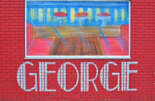 one of the windows of Georges Diner, a red brick building, painted with a scene of the interior of the restaurant.