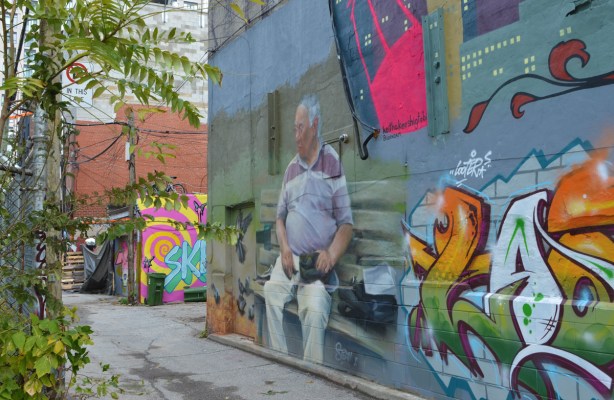 murals and street art in el mocambo lane, man on a bench with pigeons,