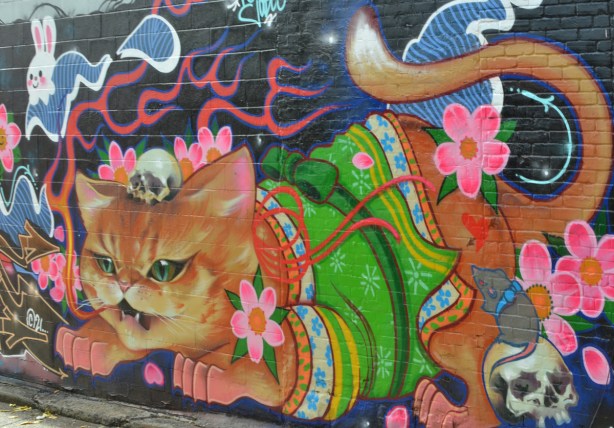 cat mural in el mocambo lane, cat wearing green coat, pink flowers and some white smiling bunnies too
