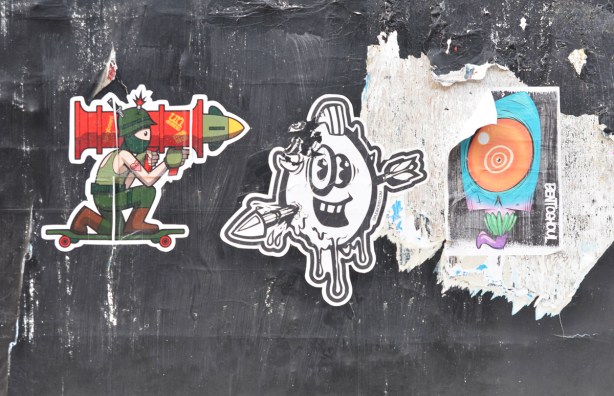 pasteups on a black wall, an urban ninja squadron with a large missile, a spudbomb and another poster like graffiti by bentoghoul