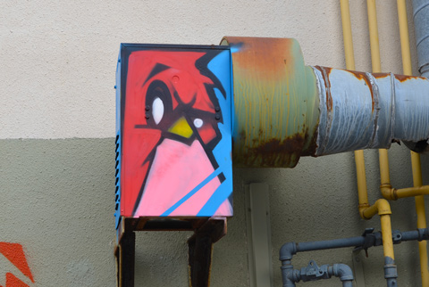 small red angry bird painting on a box in a lane
