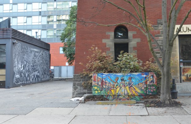 painting on metal street box in front of Alumni theater on Berkeley street, beside laneway with another black and white mural on side of building
