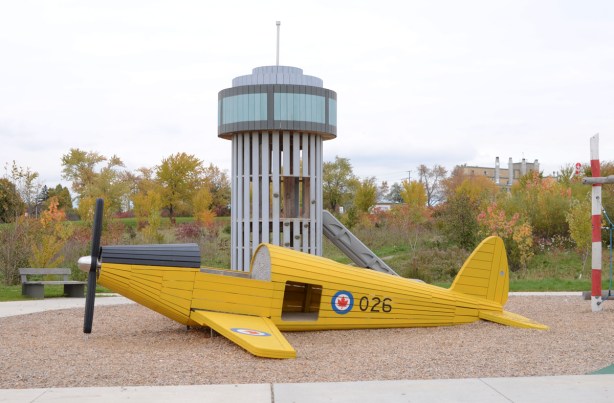 playground at Downsview Park, yellow wood airplane on ground with pretend control tower 