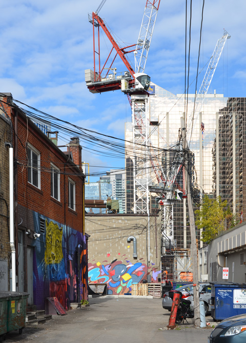 an alley behind Yonge street just north of Sheppard, construction of condos, with cranes, in the bacground, murals and street art on the back of some of the buildings