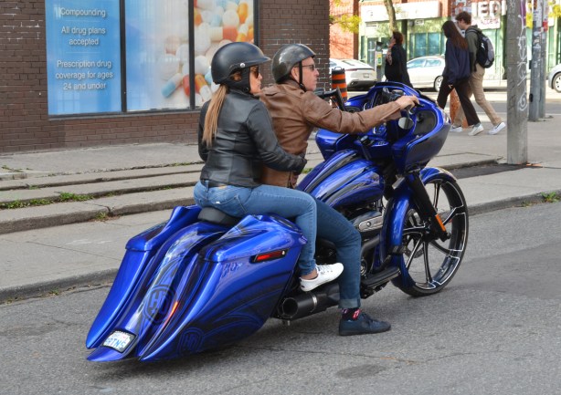 a man drives a fancy blue motorcycle with a woman passenger on the back