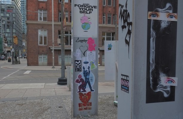 metal pole with graffiti stickers on them