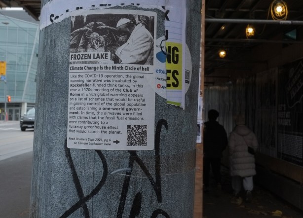 poster on a utility pole, lots of words with first line being climate change is the ninth circle of hell 