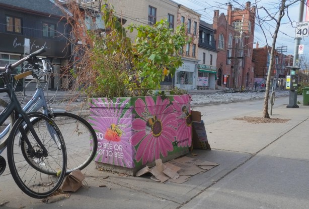 concrete planter on Queen West painted pink with picture of daisies and bees with words to bee or not to bee