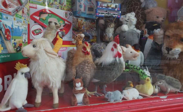 games and stuffed animals in the window of a toy store - chickens, pig, snake, mice, goat, sheep