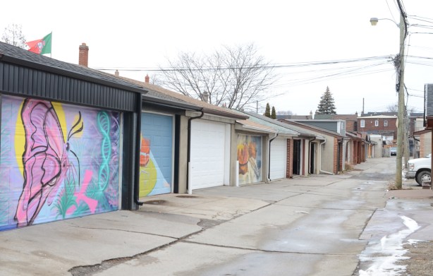 garages in a laneway in Toronto, some garage doors have murals and street art painted on them