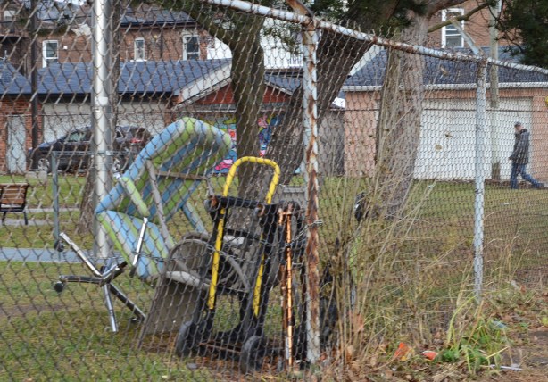 jumble of chairs and other objects on a lawn, behind a chainlink fence