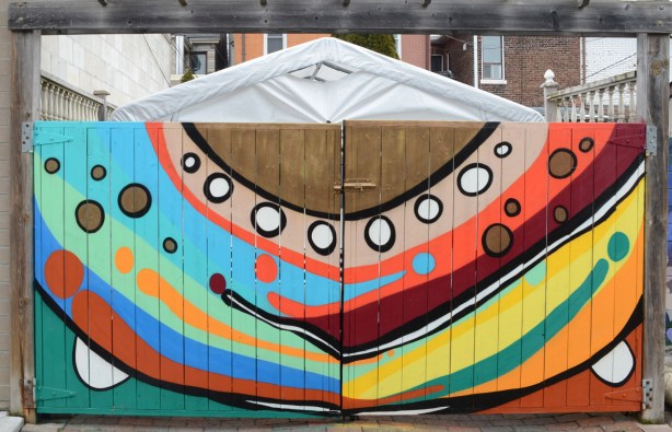 street art on a wood gate across the back of a garage, patterns of circles and semi circles