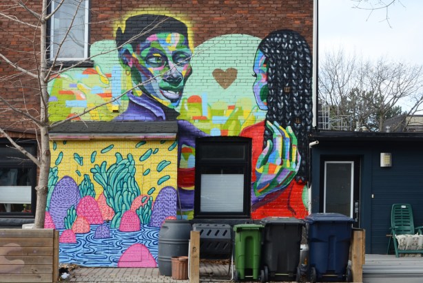 murals on the side of a house, a man and a woman with black curly hair 