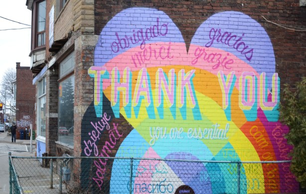 a mural on a brick wall on the side of a building on Davenport, a thank you to essential workers during covid, thank you written in many languages 