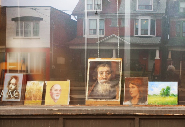 paintings in a window, with window reflections, of Art Academy of Canada