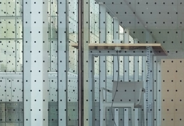 a chair and desk inside a building but facing out, close to the window